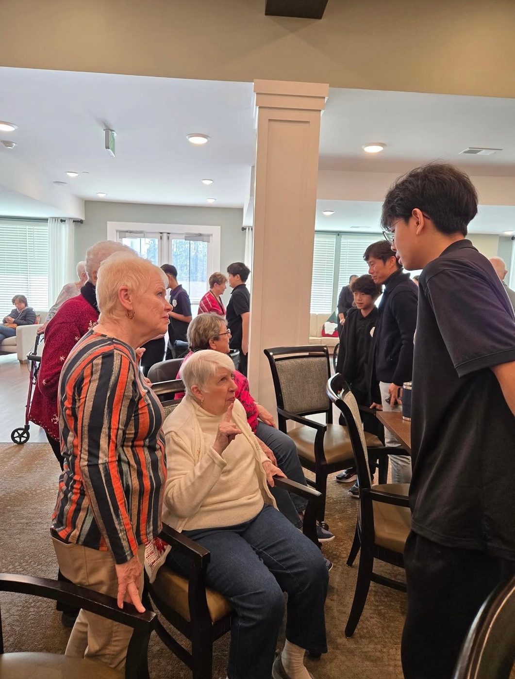 A GYCO student musician visiting with seniors after a performance at a partner community