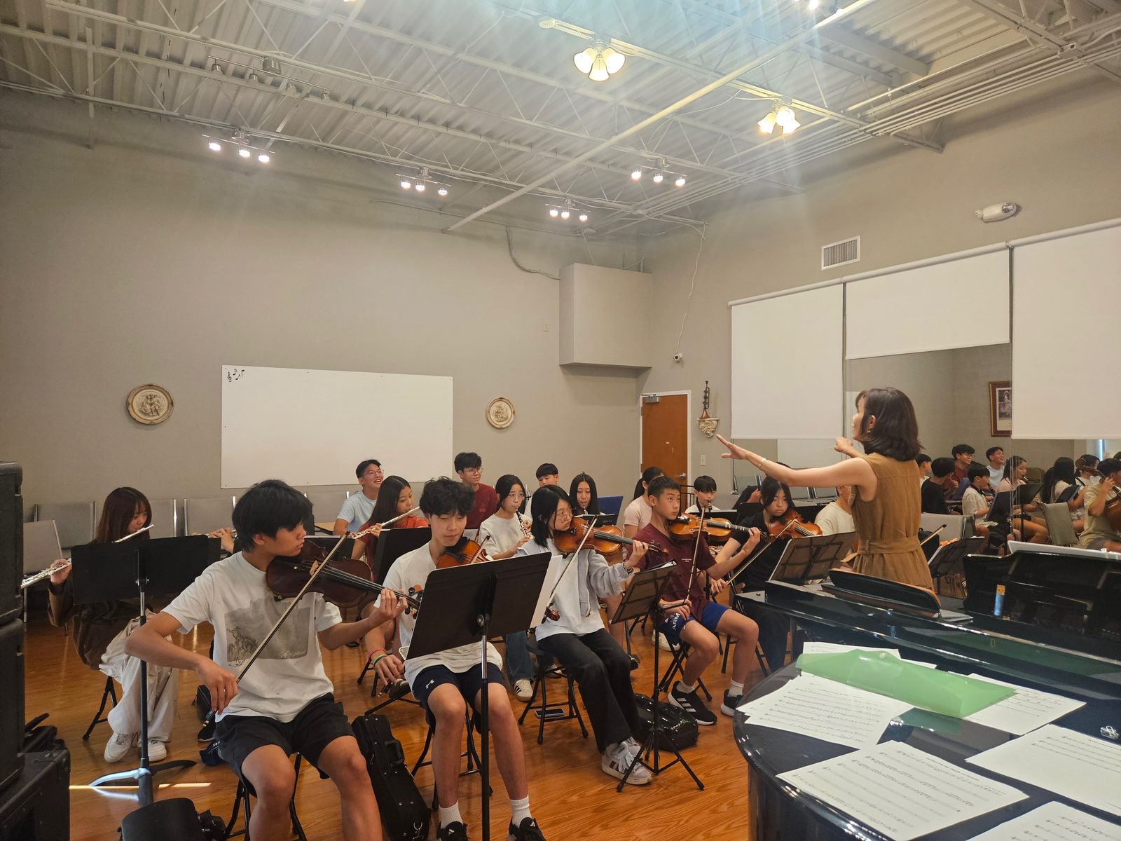 Conductor leading violins, flutes, and clarinets through the program at a summer rehearsal