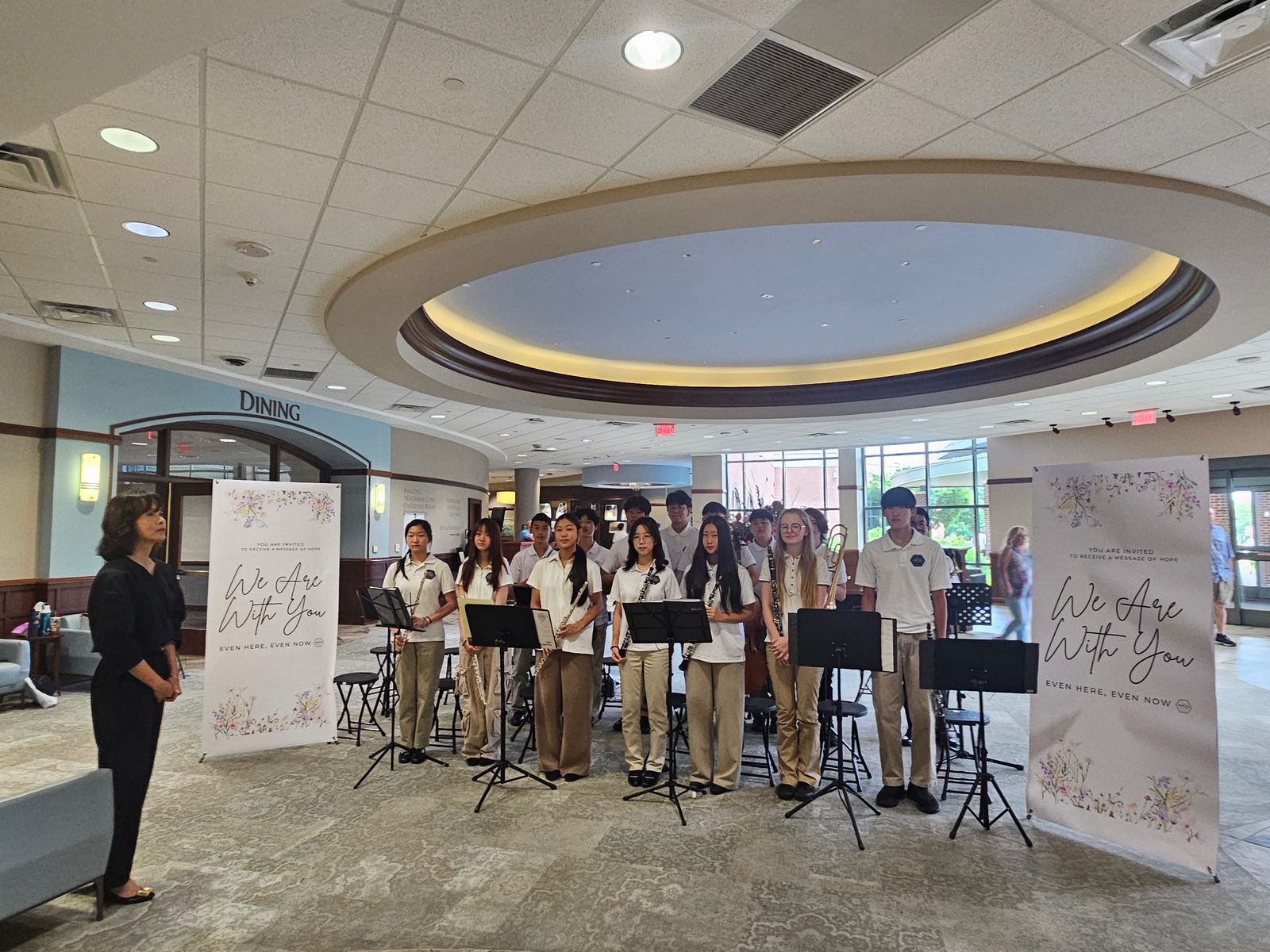 GYCO student wind ensemble performing beneath the rotunda in the City of Hope Atlanta lobby, framed by We Are With You banners