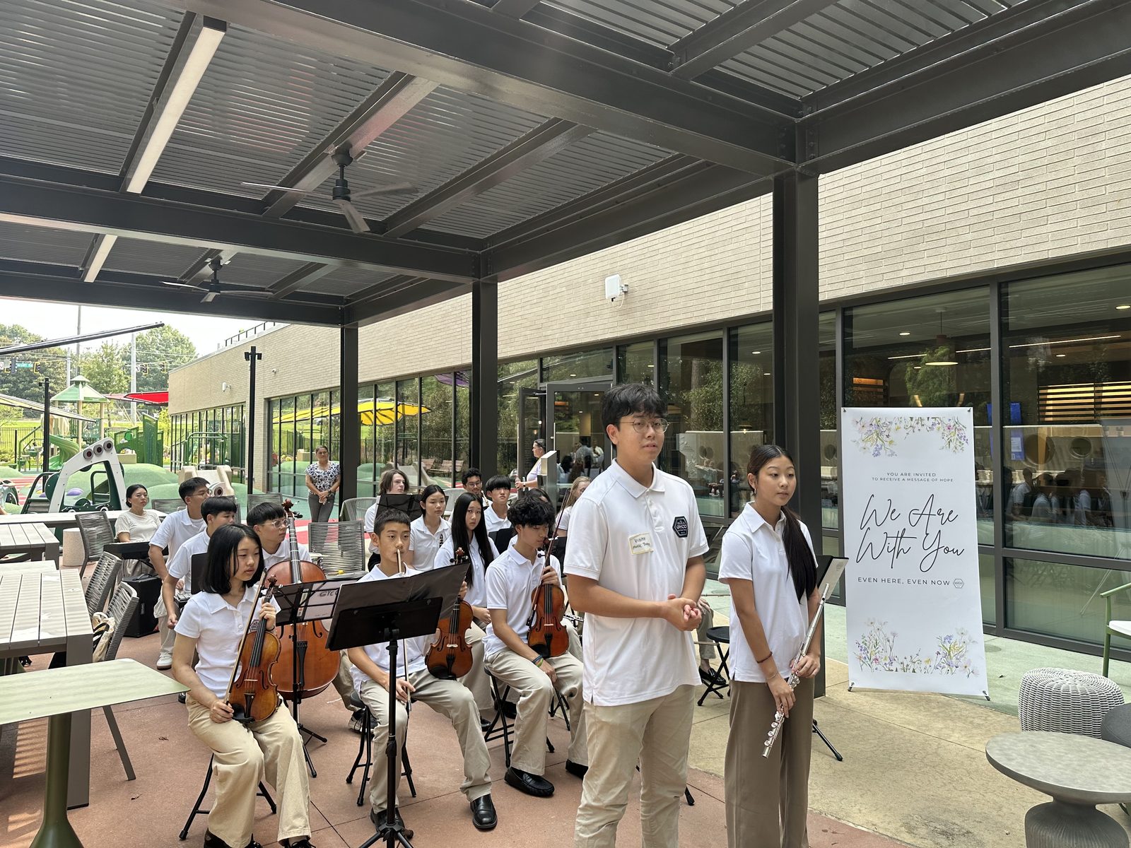 Student hosts welcoming listeners as the ensemble prepares to perform on the outdoor patio at Ronald McDonald House Atlanta