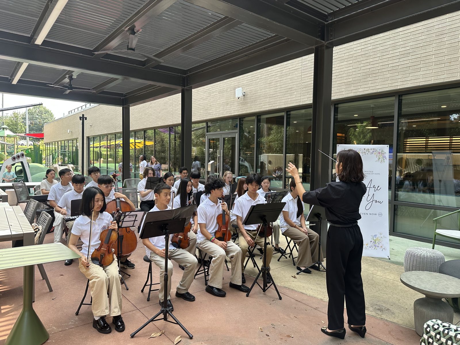 Conductor leading the GYCO string ensemble during an outdoor performance at Ronald McDonald House Atlanta