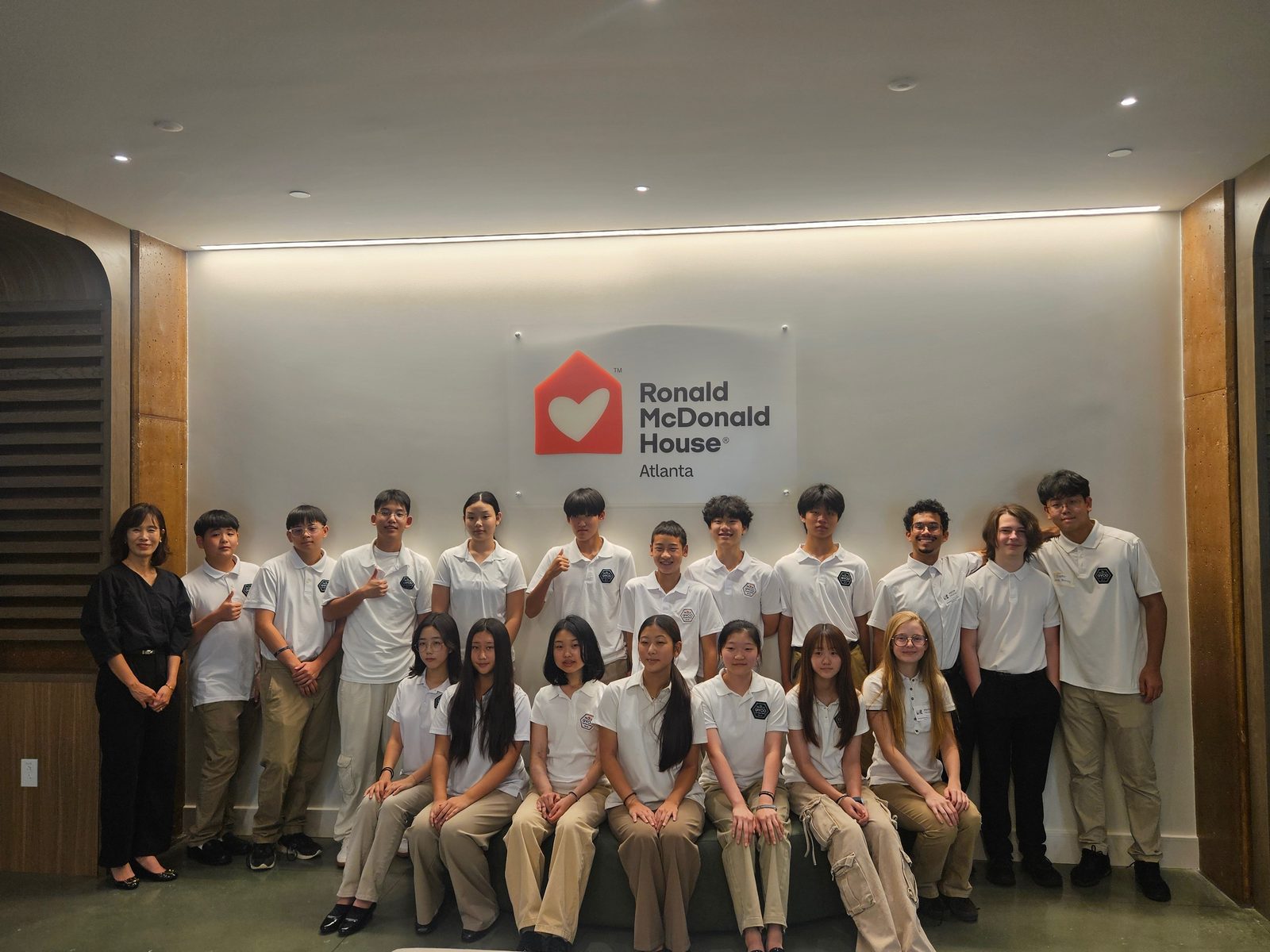 GYCO students and their conductor gathered beneath the Ronald McDonald House Atlanta sign after their performance